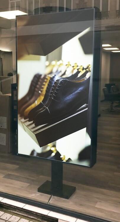 Paires de chaussures affichées sur écran dynamique dans une vitrine.