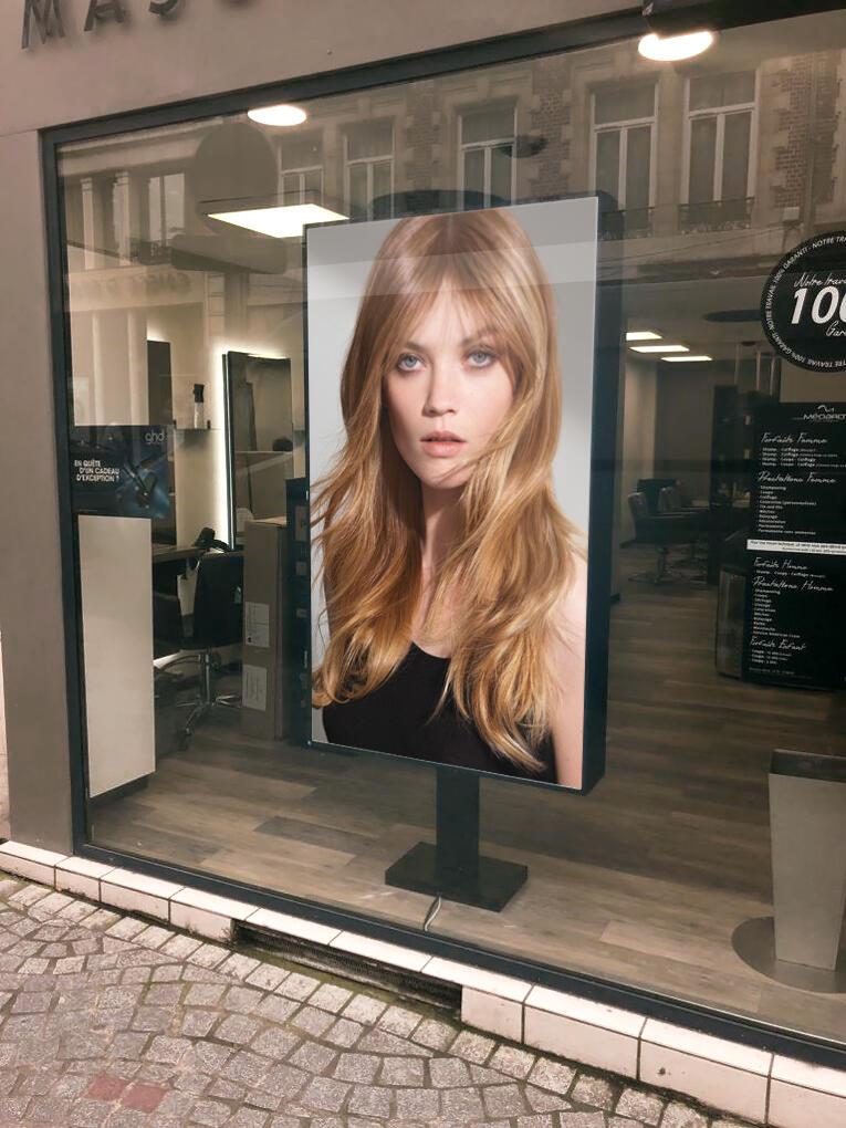 Ecran d'affichage dynamique dans la vitrine d'un salon de coiffure.