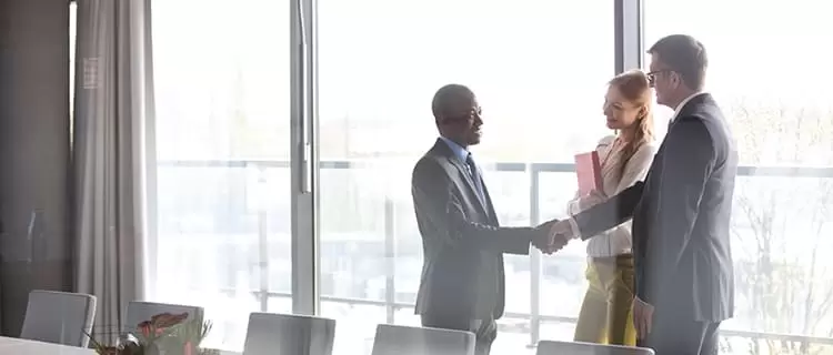 Deux hommes et une femme se rencontrent dans une salle de réunion.