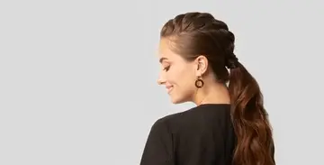 Femme brune de dos avec queue de cheval regarde à gauche.