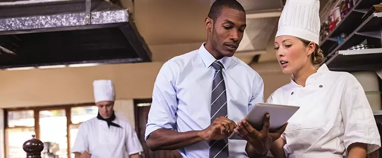 Homme qui regarde une tablette avec une femme en tenue professionnelle