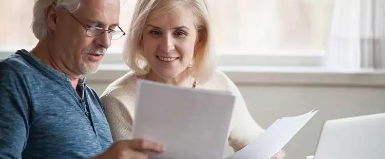 Personnes séniores sur un canapé en train de vérifier des papiers